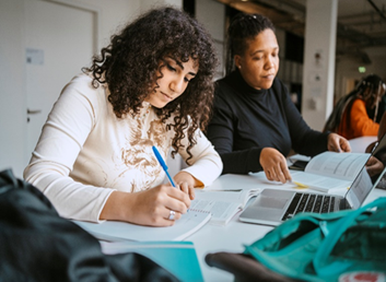 A group of people are on a course, sitting at a table making notes. There is an open laptop on the table.